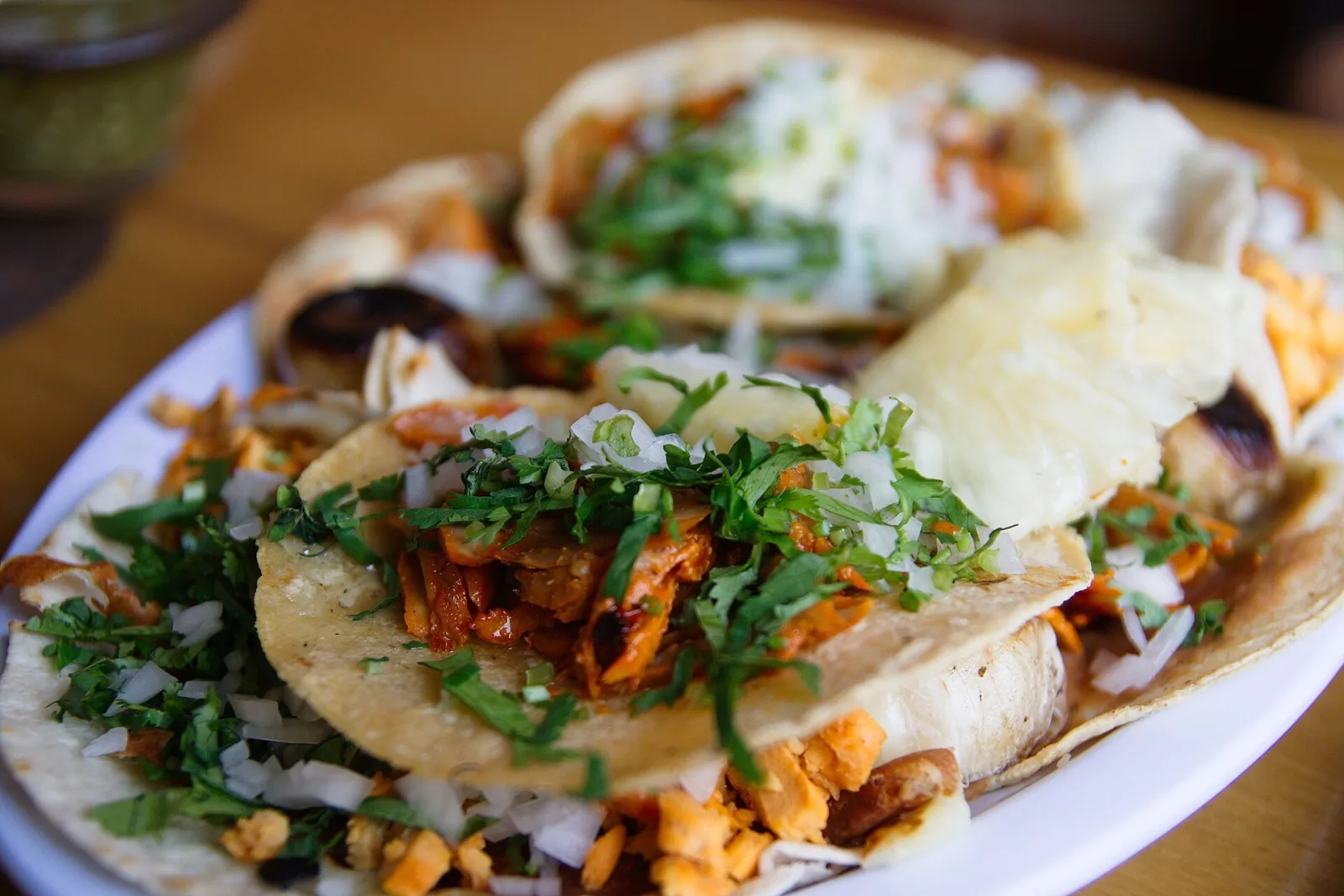 A plate of tacos al pastor topped with onion and cilantro. The photo was not taken at a Horizon West restaurant.